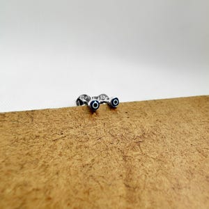 Puede incluir: Un par de pendientes de botón de plata con amuletos de ojo turco azul y blanco.