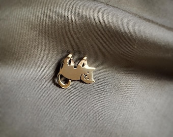 Może przedstawiać: Złota metalowa szpilka w kształcie kota, z wygiętym grzbietem i głową zwróconą w bok. Kot leży na plecach.