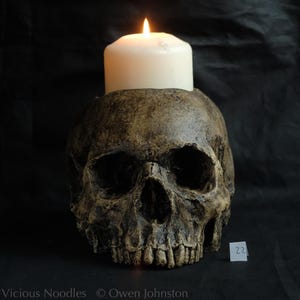 Human skull candle holder, life size, made from polymerised plaster and painted for a highly weathered appearance