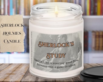 May include: A lit white candle in a glass jar with a label that reads "SHERLOCK'S STUDY." The candle has a black lid and the text "SHERLOCK HOLMES CANDLE" on a separate piece of paper. The candle's scent is described as a roaring fire, tobacco, and a game.