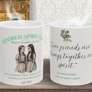 May include: White ceramic mug featuring the text "Kindred Spirit Club" and "True friends are always together in spirit." The mug has illustrations of two girls and a floral design. The mug also has the text "Est 1908".