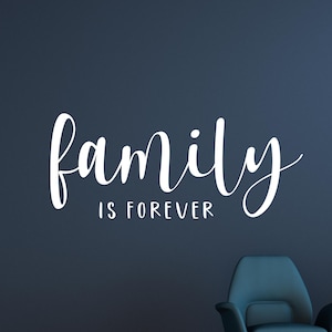 May include: A white wall decal featuring the word family in a large, flowing script font, positioned above the words IS FOREVER in a smaller, clean, sans-serif typeface. The text is displayed against a solid, dark navy blue wall surface.