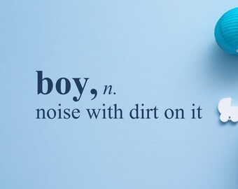 May include: A light blue wall decal featuring the dark blue text "boy, n. noise with dirt on it" in a dictionary-style font. The design includes a small white silhouette of a baby carriage and a partial view of a blue paper lantern in the corner.