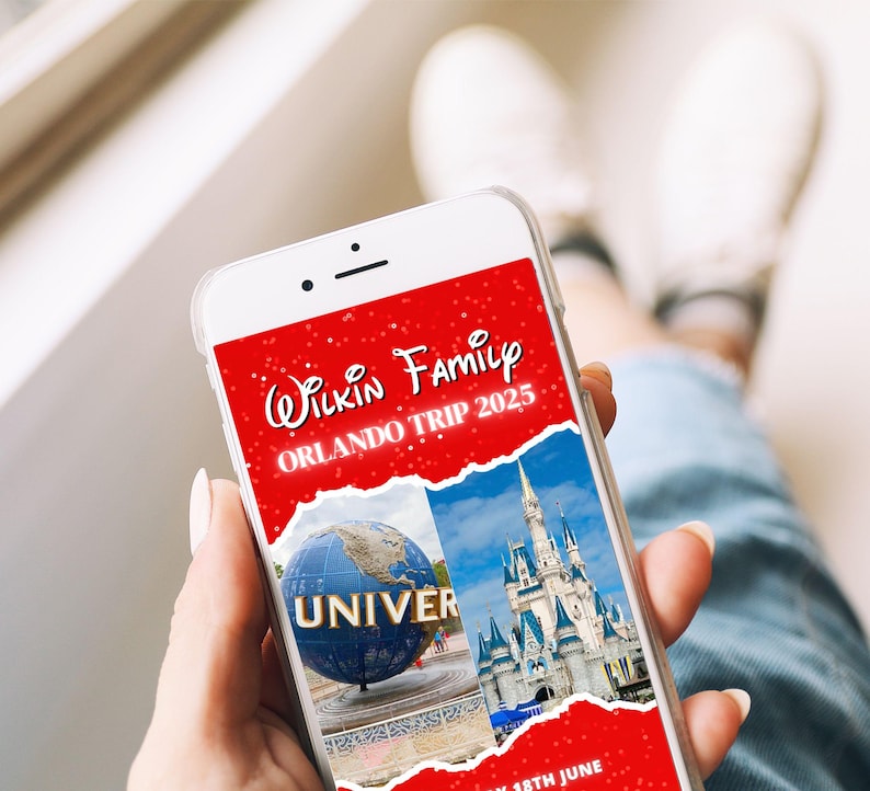 May include: A smartphone displays a red graphic with the text "Wilkin Family Orlando Trip 2025." The screen shows images of a globe with "UNIVER" and a castle. The phone is held in a hand, with white shoes visible in the background.