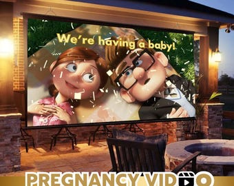 Puede incluir: Una pantalla al aire libre muestra una imagen de dibujos animados de una pareja con el texto "We're having a baby!". Las palabras "PREGNANCY VIDEO" y "Instant access get your video today" están en la parte inferior de la pantalla.