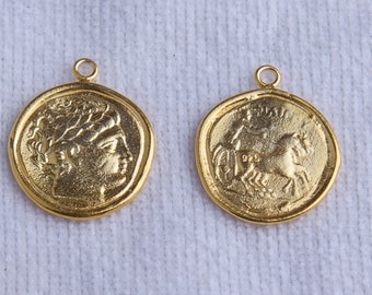 May include: Two gold-colored pendants, one with a profile of a woman with a crown and the other with a chariot pulled by a horse.