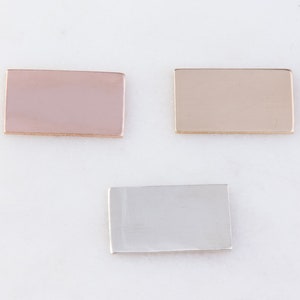 May include: Three rectangular metal blanks in different colors: rose gold, gold, and silver. These blanks are ideal for jewelry making or other craft projects.