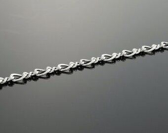 May include: A silver chain necklace with a delicate, interwoven design. The chain is made of small, linked ovals that create a subtle, textured look.