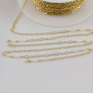 May include: Gold chain with a diamond-shaped link pattern. The chain is coiled on a white surface.