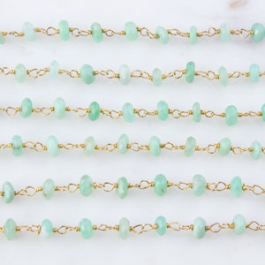 Pode incluir: Um fio de contas de pedras preciosas verde claro enfiadas em uma corrente de ouro. As contas s&atilde;o facetadas e t&ecirc;m uma forma ligeiramente irregular. A corrente &eacute; feita de pequenos elos delicados.