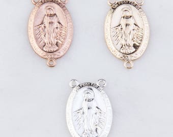 May include: Three oval-shaped metal charms featuring an image of the Virgin Mary. The charms are in gold, silver, and rose gold.