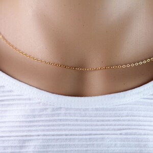Pu&ograve; includere: Una delicata collana a catena d'oro su un manichino bianco.
