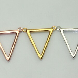 May include: Three triangle-shaped metal charms in gold, silver, and rose gold. Each charm has a loop at the top for attaching to a necklace or bracelet.