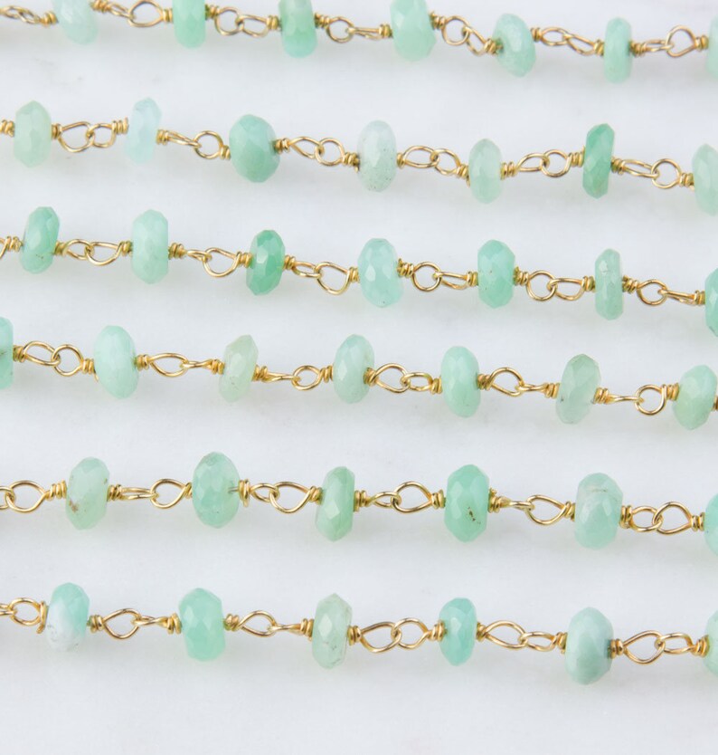 Pode incluir: Uma linha de contas de pedras preciosas verde claro enfiadas em uma corrente de ouro. As contas s&atilde;o facetadas e t&ecirc;m uma forma ligeiramente irregular.
