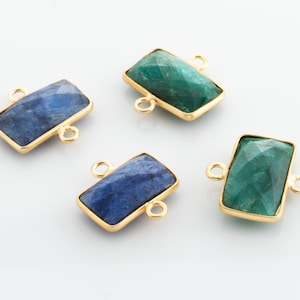 May include: Four gemstone connector charms with gold-toned metal accents. Two charms are blue and two are green.