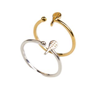 May include: Two rings featuring a tennis racket design. One ring is gold and the other is silver.
