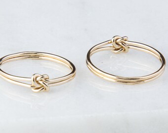 May include: Two gold rings with a knot design. The rings are simple and elegant.