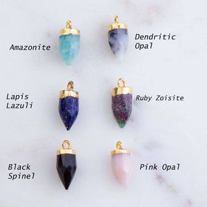 May include: Eight gold-plated gemstone pendants with different colored stones, including amazonite, dendritic opal, lapis lazuli, ruby zoisite, black spinel, and pink opal.
