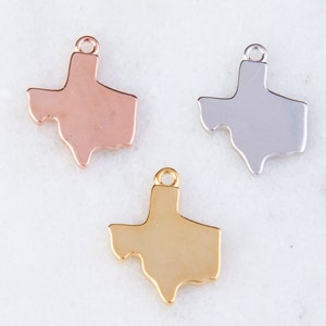 May include: Three metal charms shaped like the state of Texas. The charms are in gold, silver, and rose gold.