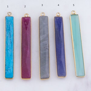 May include: Five gold-plated bar pendants with different colored stones. The stones are turquoise, pink, gray, blue, and green.