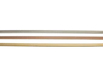 May include: Three metal strips in silver, rose gold, and gold. The strips are flat and rectangular.