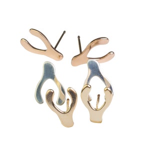 May include: A pair of silver and gold earrings with a unique, abstract design. The earrings are shaped like a wishbone.