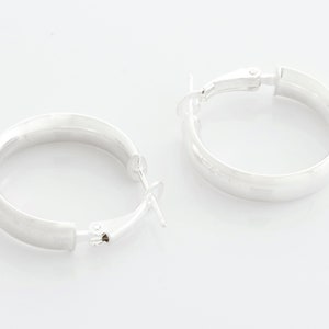 May include: A pair of silver hoop earrings with a hinged clasp.