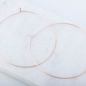 May include: A pair of gold hoop earrings. The hoops are thin and delicate, and they are a simple and elegant design.