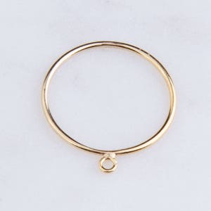 May include: A gold ring with a small loop hanging from the bottom.