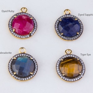 May include: Four round gemstone pendants with gold settings and a clear crystal halo. The stones are dyed ruby, dyed sapphire, labradorite, and tiger eye.