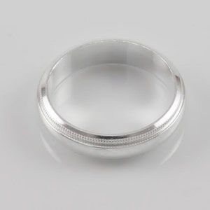 May include: A silver wedding band with a simple, textured design.