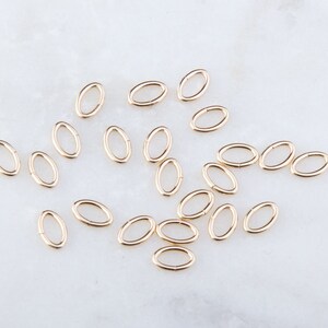 May include: A collection of 20 gold oval jump rings. The jump rings are small and delicate, perfect for jewelry making.