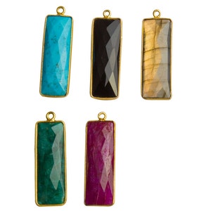 May include: Six gold-plated pendant charms with different colored gemstone inserts. The charms are rectangular and have a faceted design. The gemstones are turquoise, black, brown, green, and pink.