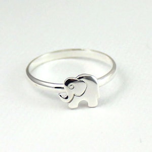 May include: A silver ring with an elephant design. The elephant is facing to the right and has a small trunk.