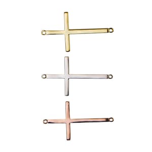 May include: Three metal cross charms in gold, silver, and rose gold. Each cross charm has a loop on each end for attaching to a necklace or bracelet.