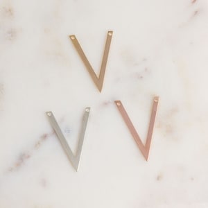 May include: Three metal V-shaped charms in gold, silver, and rose gold.
