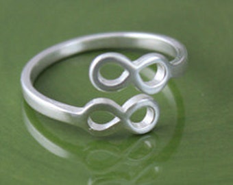 Peut inclure: Une bague en argent en forme de symbole infini avec deux symboles infinis entrelacés. La bague est en métal poli et a une finition lisse.