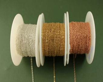 May include: Three spools of chain, one silver, one gold, and one rose gold. The chain is on white spools.