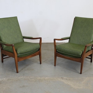 May include: Two mid-century modern armchairs with a dark wood frame and green upholstery.