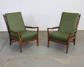 May include: Two mid-century modern armchairs with a dark wood frame and green upholstery.