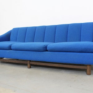 May include: A blue tufted sofa with wooden legs. The sofa has a classic design and is upholstered in a soft, textured fabric.