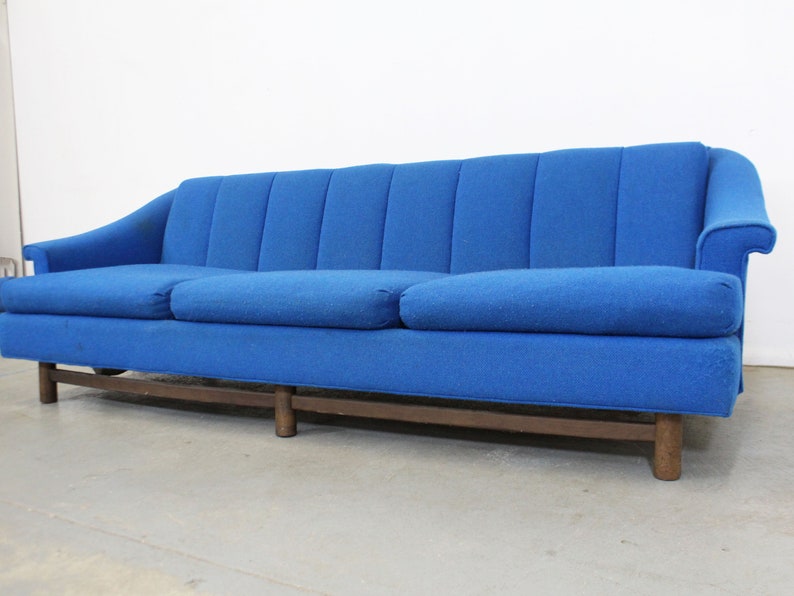 May include: A blue tufted sofa with wooden legs. The sofa has a classic design and is upholstered in a soft, textured fabric.