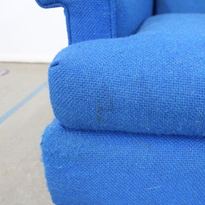 May include: Close-up of a blue fabric sofa with a textured weave. The sofa has a tufted back and a deep seat.