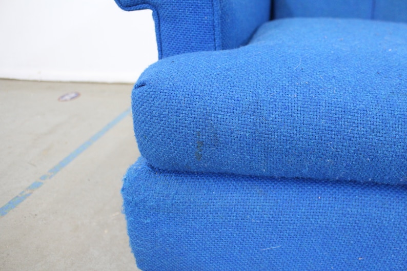 May include: Close-up of a blue fabric sofa with a textured weave. The sofa has a tufted back and a deep seat.