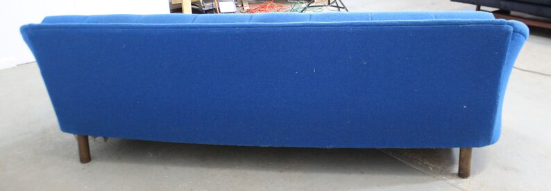 May include: A blue fabric sofa with a curved back and wooden legs.