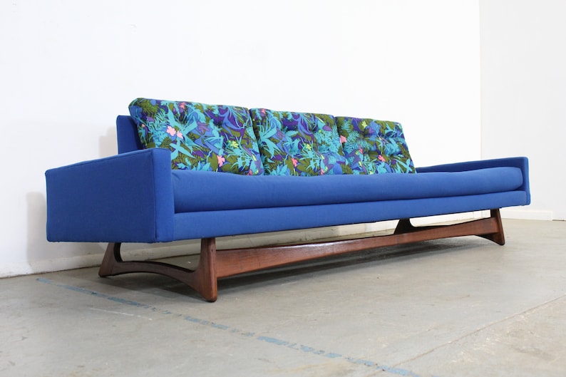 May include: A blue mid-century modern sofa with a wood frame and floral patterned cushions.