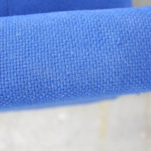 May include: Close-up of a blue fabric with a woven texture. The fabric is smooth and appears to be made of a soft material.