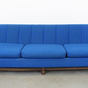 May include: A blue three-seater sofa with a tufted back and wooden legs.