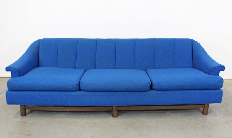 May include: A blue three-seater sofa with a tufted back and wooden legs.