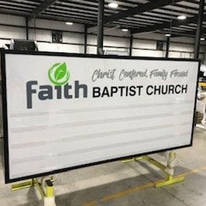 Puede incluir: Un letrero blanco con borde negro y un logotipo "faith" en negro y gris. El letrero tambi&eacute;n tiene un logotipo de hoja verde y el texto "Christ Centered, Family Focused" y "BAPTIST CHURCH".